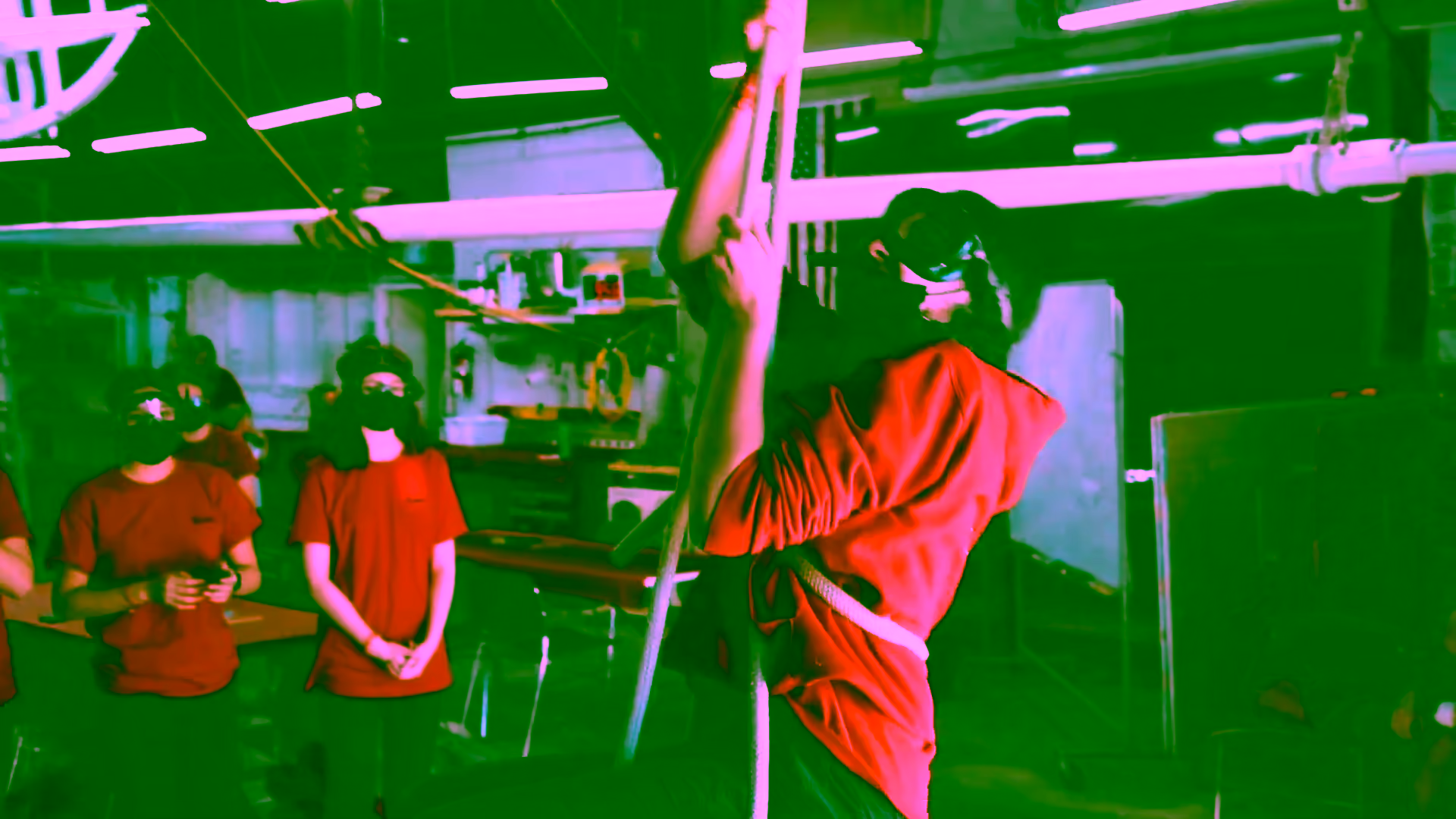 A Sea Scout climbing a rope in goggles as her crew watches